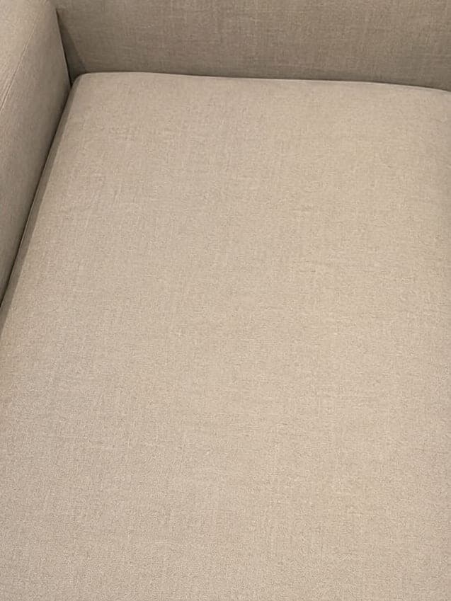 La même assise de canapé en tissu beige, au tissu uniforme après nettoyage